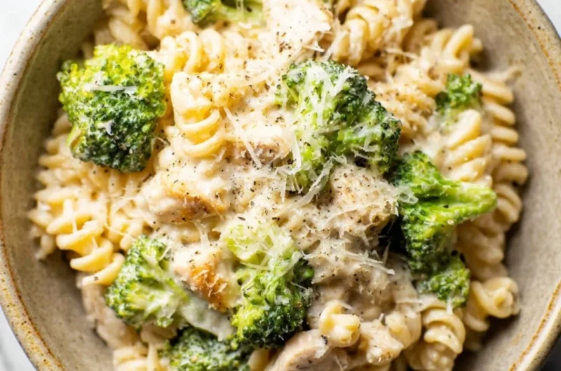 A vibrant bowl of Chicken Broccoli Pasta garnished with fresh herbs and parmesan cheese.