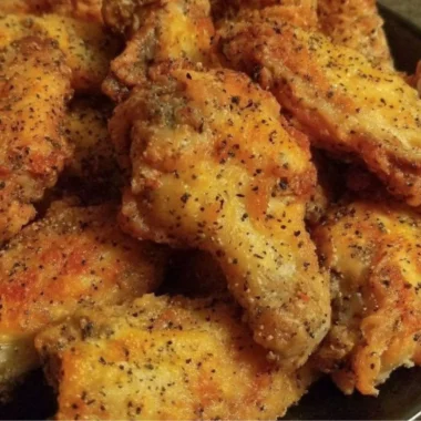 Crispy lemon pepper chicken wings served with fresh lemon slices and herbs.