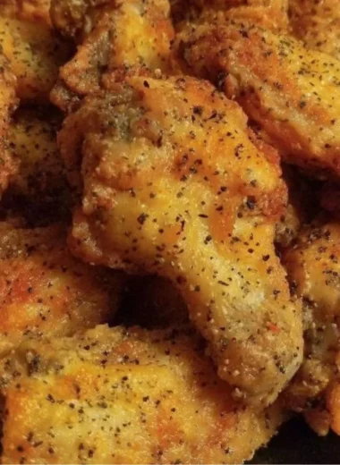 Crispy lemon pepper chicken wings served with fresh lemon slices and herbs.