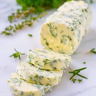 Delicious garlic butter spread on fresh bread with herbs and garlic cloves
