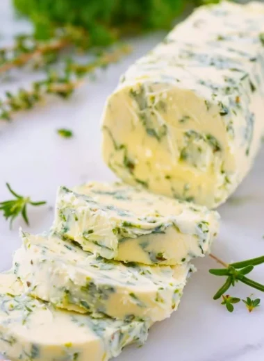 Delicious garlic butter spread on fresh bread with herbs and garlic cloves