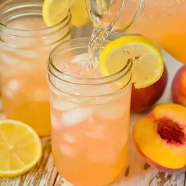 Glass of homemade peach lemonade with fresh peaches and lemons