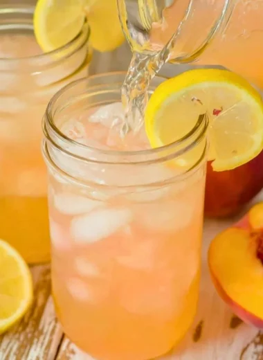 Glass of homemade peach lemonade with fresh peaches and lemons