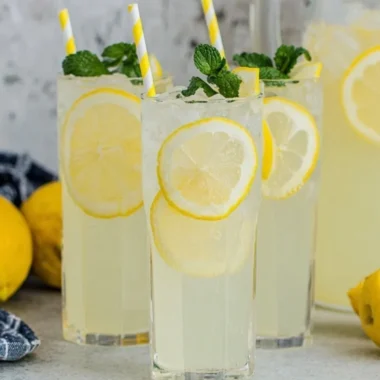 A glass of old-fashioned homemade lemonade with fresh lemons and mint.