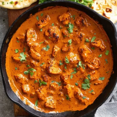 Bowl of Chicken Tikka Masala with naan and garnish