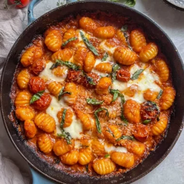 Creamy tomato gnocchi garnished with fresh basil and grated cheese.