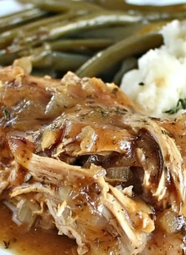 Delicious Crock Pot Mississippi Chicken served with sides on a rustic table