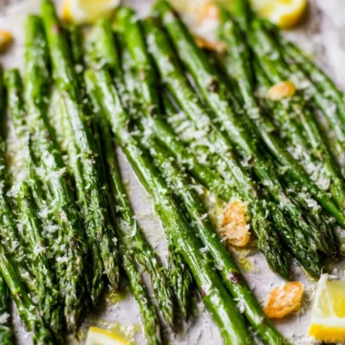Oven-roasted garlic Parmesan asparagus on a plate with a sprinkle of cheese