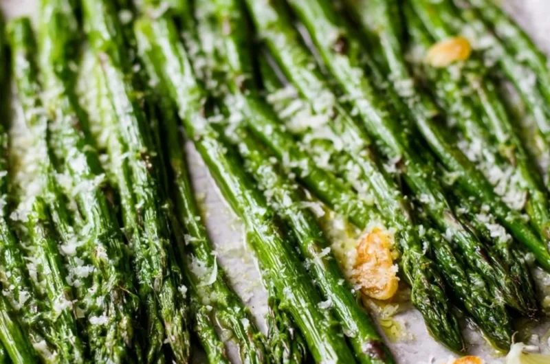 Oven-roasted garlic Parmesan asparagus on a plate with a sprinkle of cheese