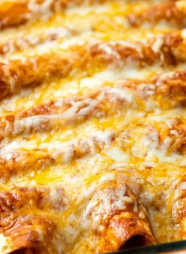 Plate of restaurant-style red cheese enchiladas topped with cheese and fresh herbs