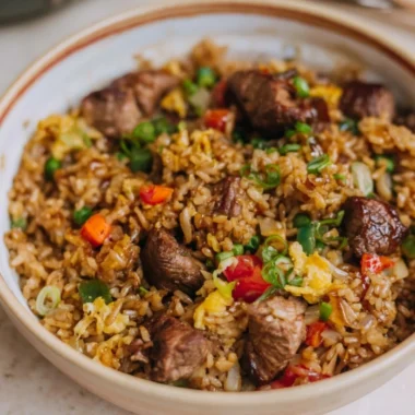 Delicious cozy steak fried rice topped with fresh vegetables and savory seasoning.