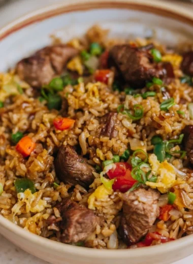 Delicious cozy steak fried rice topped with fresh vegetables and savory seasoning.