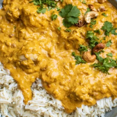 Delicious creamy Chicken Korma served with rice and garnished with herbs.