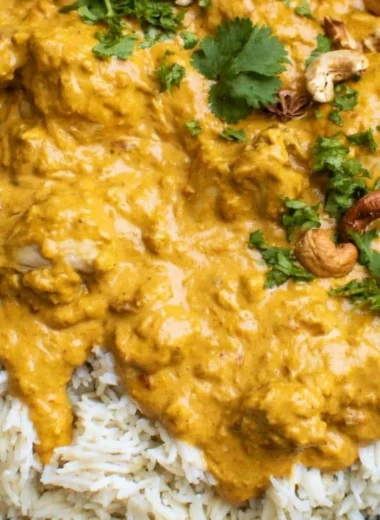 Delicious creamy Chicken Korma served with rice and garnished with herbs.