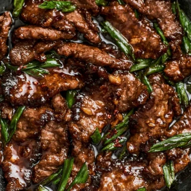 Delicious easy Mongolian beef served on a plate with green onions and rice
