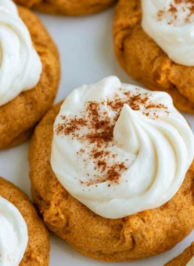 Pumpkin cookies with cream cheese frosting on a wooden table