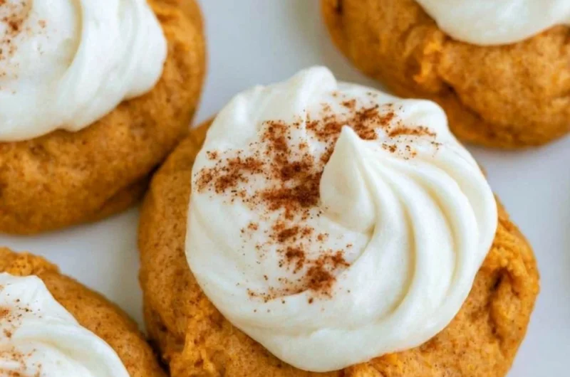 Pumpkin cookies with cream cheese frosting on a wooden table